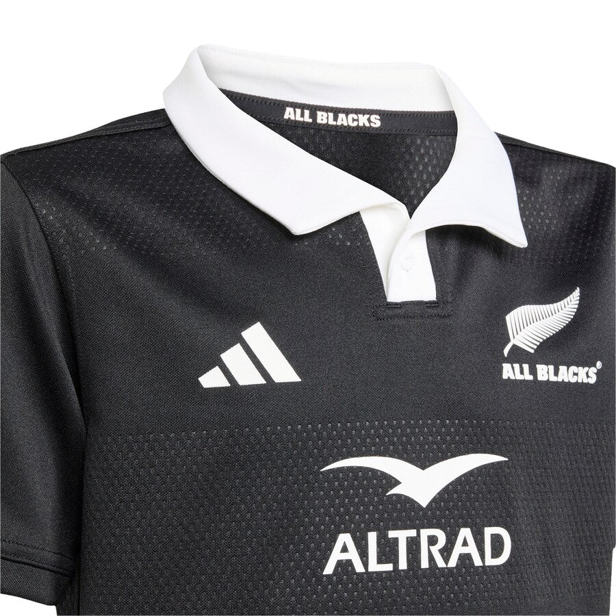 Close-up of the Youth All Blacks 25/26 Replica Home Jersey by adidas, featuring a white collar and displaying the iconic All Blacks logo, adidas branding, and Altrad sponsor.