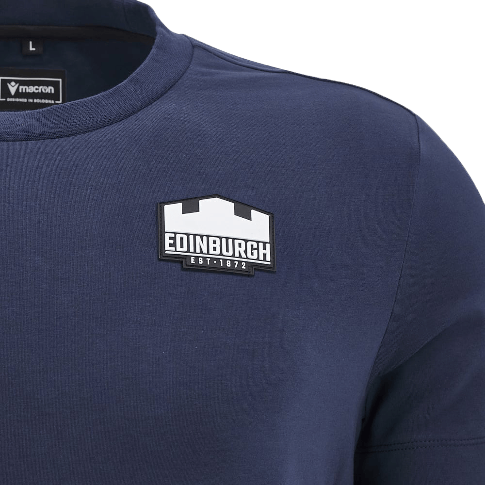 The Edinburgh 24/25 Anthem Travel Cotton T-Shirt by Macron, a heavyweight navy blue tee, showcases an Edinburgh Castle logo and "Edinburgh EST. 1872" text on the chest, combining classic style with athleisure comfort, ideal for history fans or as an Edinburgh Rugby T-shirt.