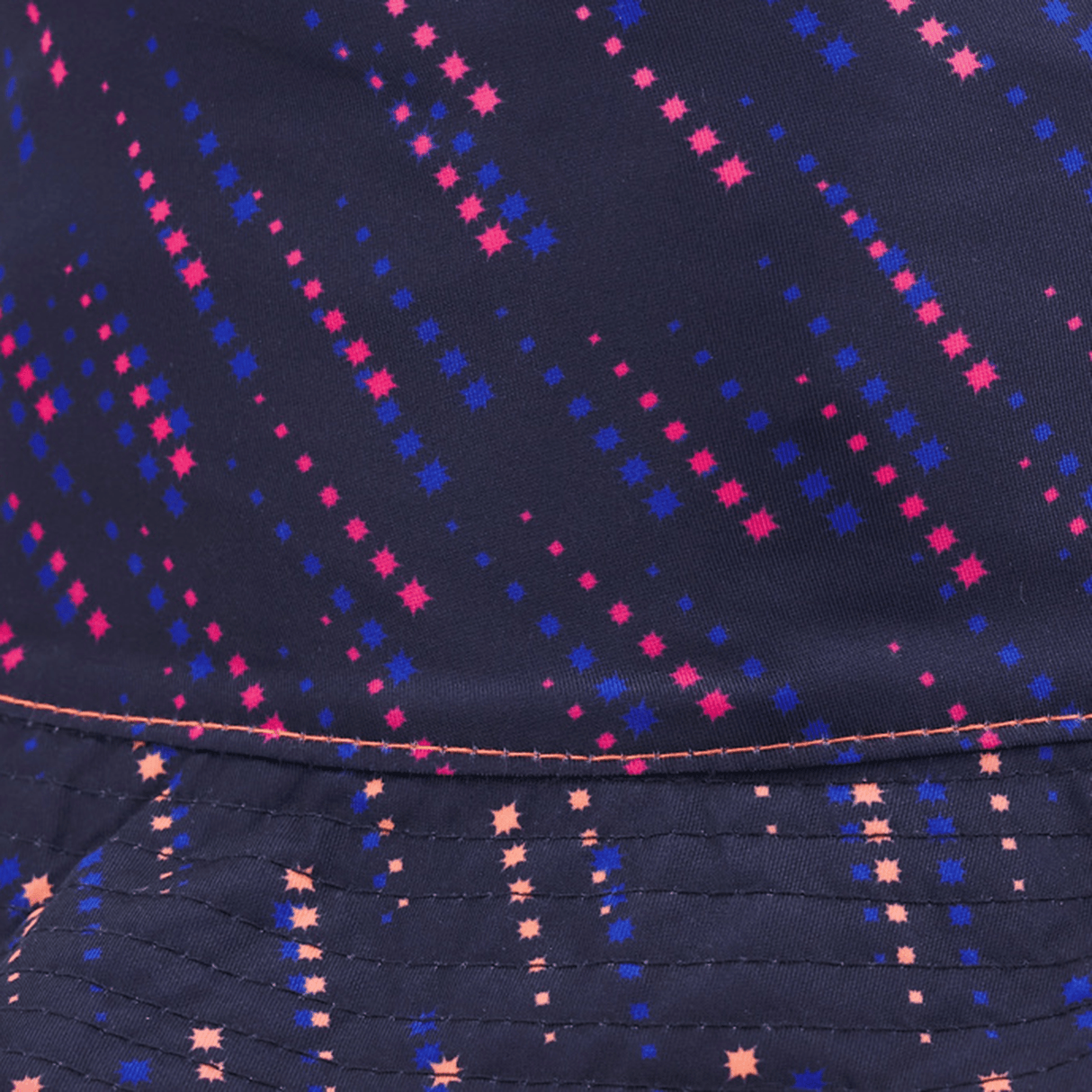 Close-up of a fabric pattern showcasing diagonal lines of pink and blue stars on a dark blue background, reminiscent of the lively designs often found on the Edinburgh 24/25 Bucket Hat by Macron.