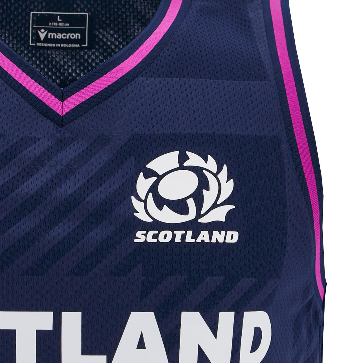 Close-up of the Scotland 25/26 Basketball Singlet by Macron in navy blue with pink trim, featuring a thistle logo and "SCOTLAND" below. Made from breathable performance fabric for comfort on and off the court.