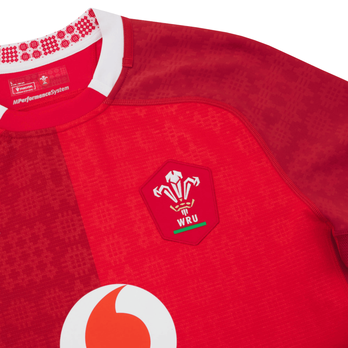 Close-up of the Wales 25/26 Authentic Matchday Home Jersey by Macron, a red rugby jersey featuring the WRU and Vodafone logos plus a patterned collar—official matchwear from Macron.
