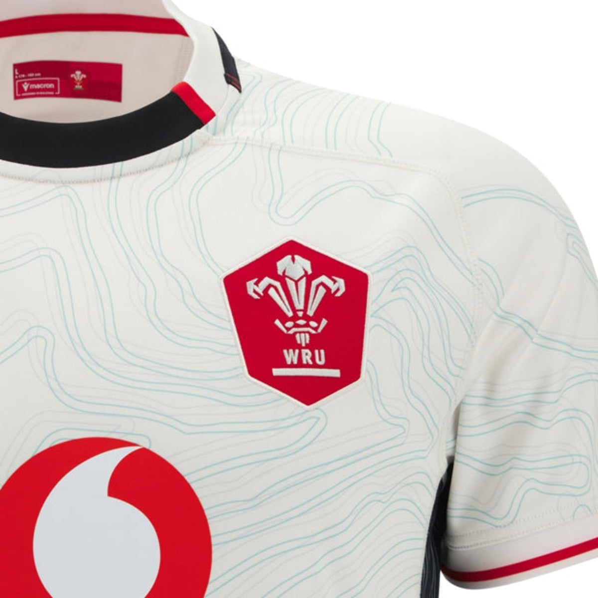 Close-up of the Wales 25/26 Replica Away Jersey by Macron, showcasing the WRU logo, abstract line patterns, and a red sponsor logo—a top-performance away rugby shirt crafted for style by Macron.