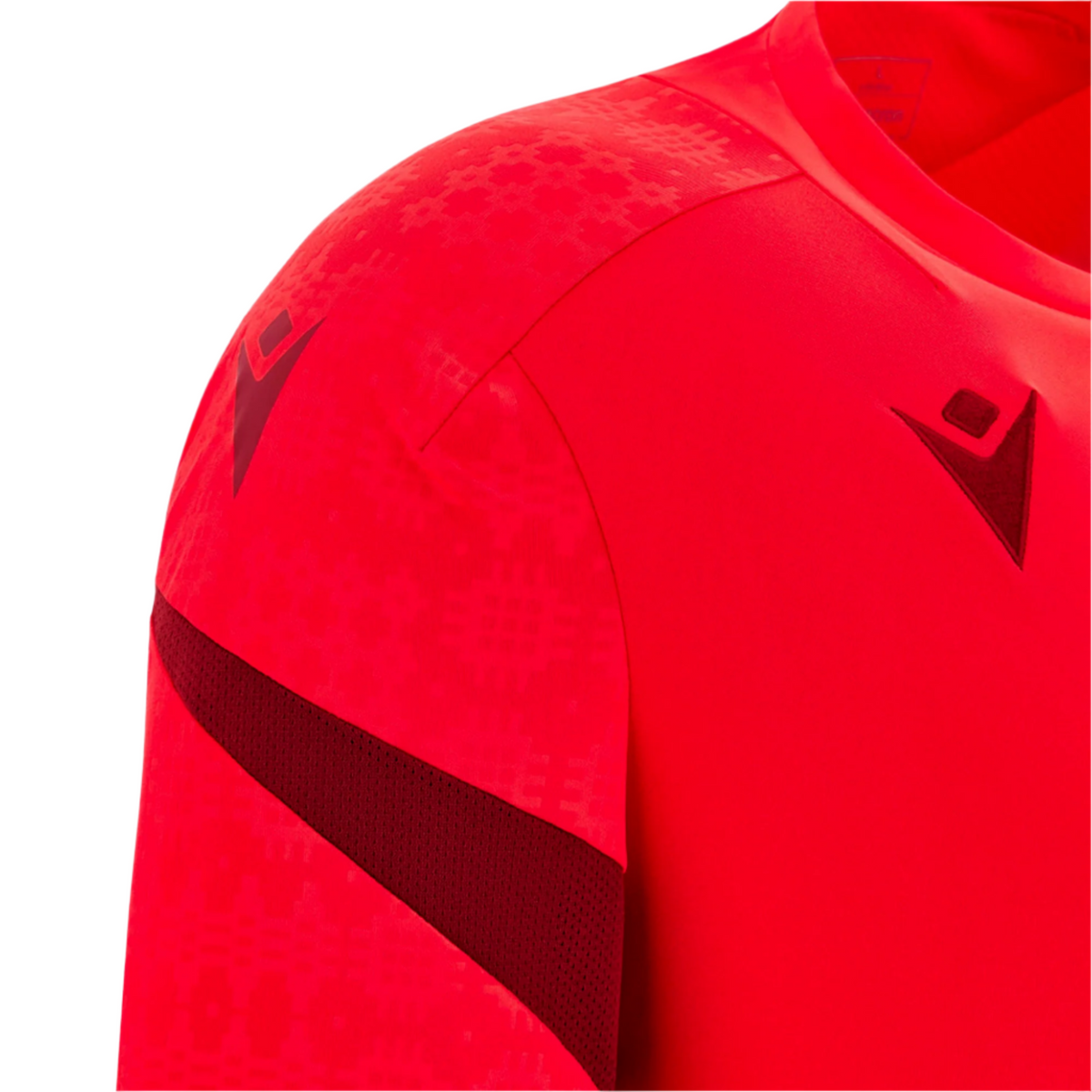Close-up of the Wales 25/26 Player Training Shirt by Macron, a red jersey with geometric patterns and dark red Macron logo details on the chest and shoulder.