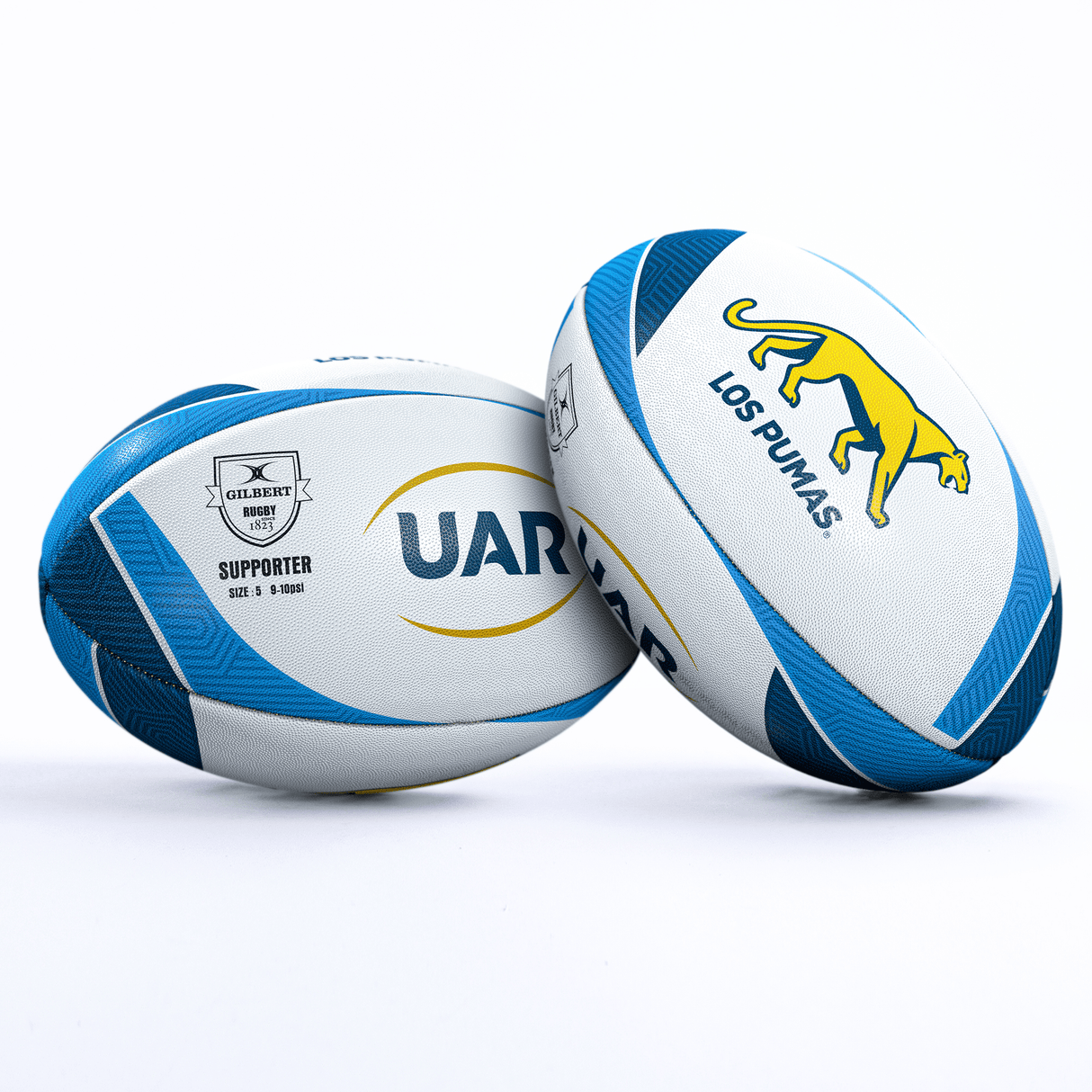 Image of two white and blue Argentina Pumas Supporters Balls by Gilbert. One features the logo of "URU" while the other displays "LOS PUMAS" with a puma symbol, representing Argentina. Both have text "GILBERT SUPPORTER" and are placed on a white surface. A perfect rugby supporter ball for fans.