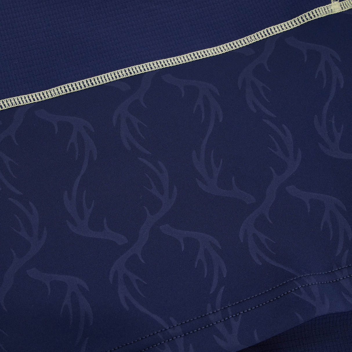 Close-up of dark blue fabric featuring a subtle antler pattern and a light-colored stitched seam near the top, highlighting the intricate details found on the Scotland SRU 26/27 Authentic Matchday Home Jersey by Macron.