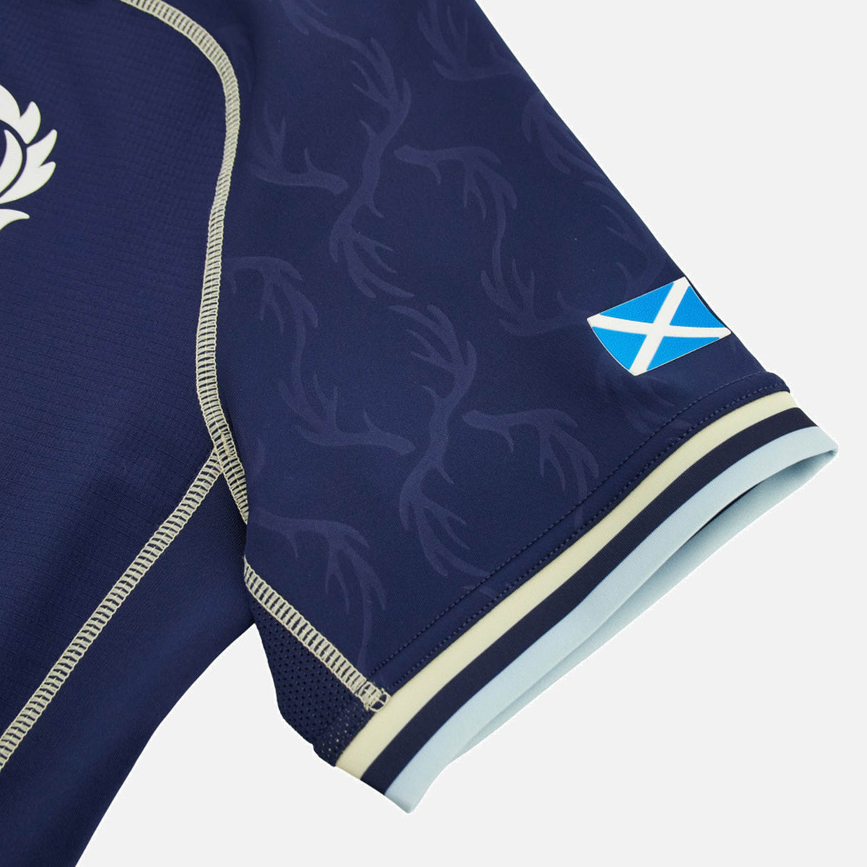 Close-up of the sleeve of the Scotland SRU 26/27 Authentic Matchday Home Jersey by Macron—a navy blue design with a subtle antler pattern and a small Scottish flag near the cuff, showcasing authentic matchday detail from Macron.