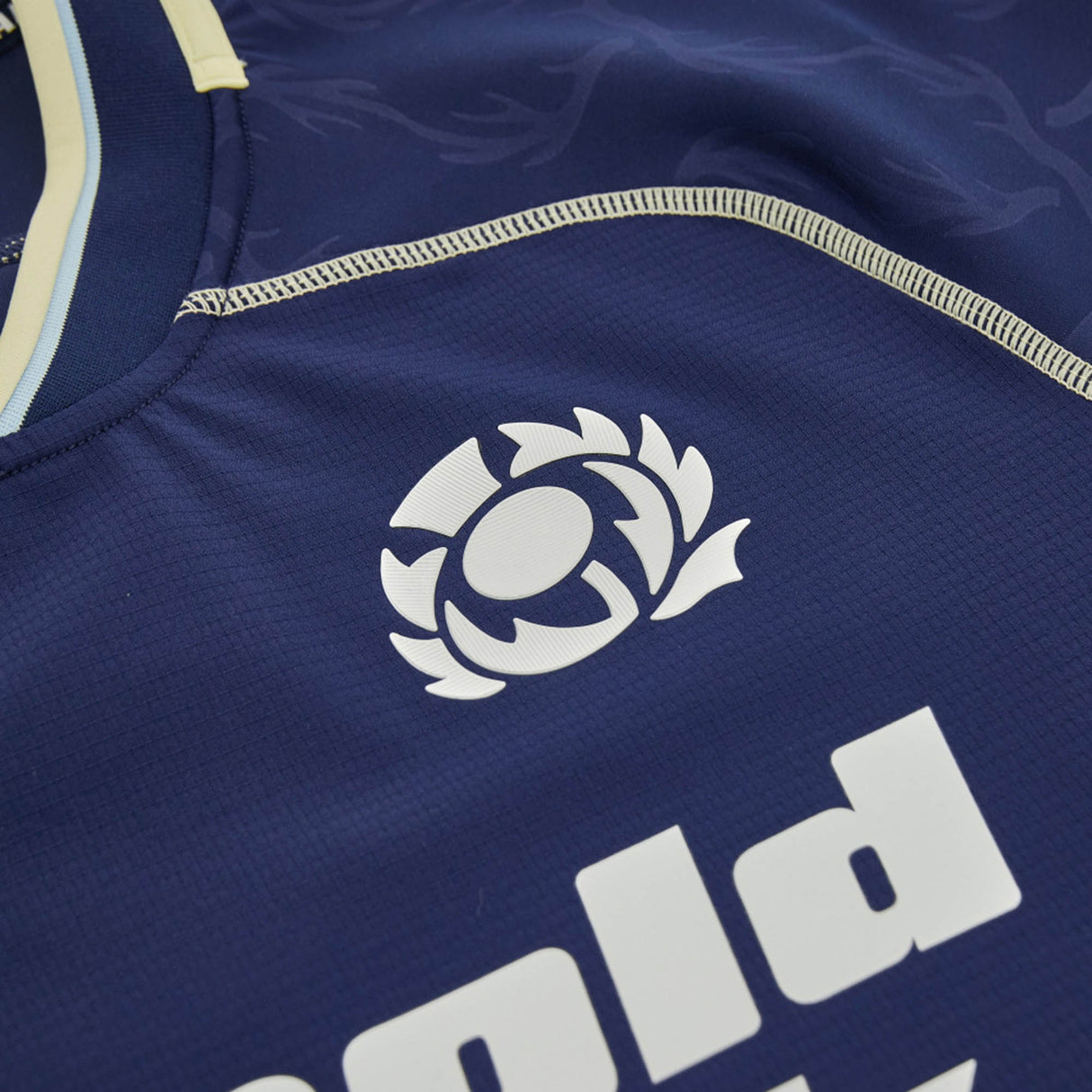 Close-up of the Scotland SRU 26/27 Authentic Matchday Home Jersey by Macron in navy blue, showcasing the white Scottish Rugby logo and part of a sponsor’s name in bold lettering—a genuine Macron authentic matchday shirt.