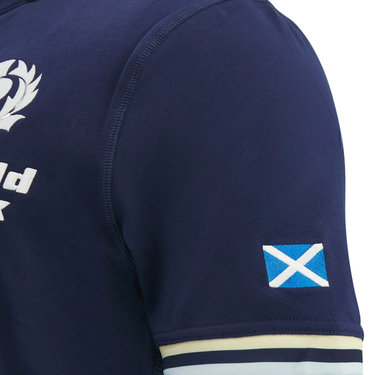 Close-up of the Scotland SRU 26/27 Cotton Replica Home Jersey by Macron in navy blue cotton, highlighting a small Scottish flag patch on the sleeve and part of a white chest logo. This Macron jersey embodies authentic team spirit in every detail.