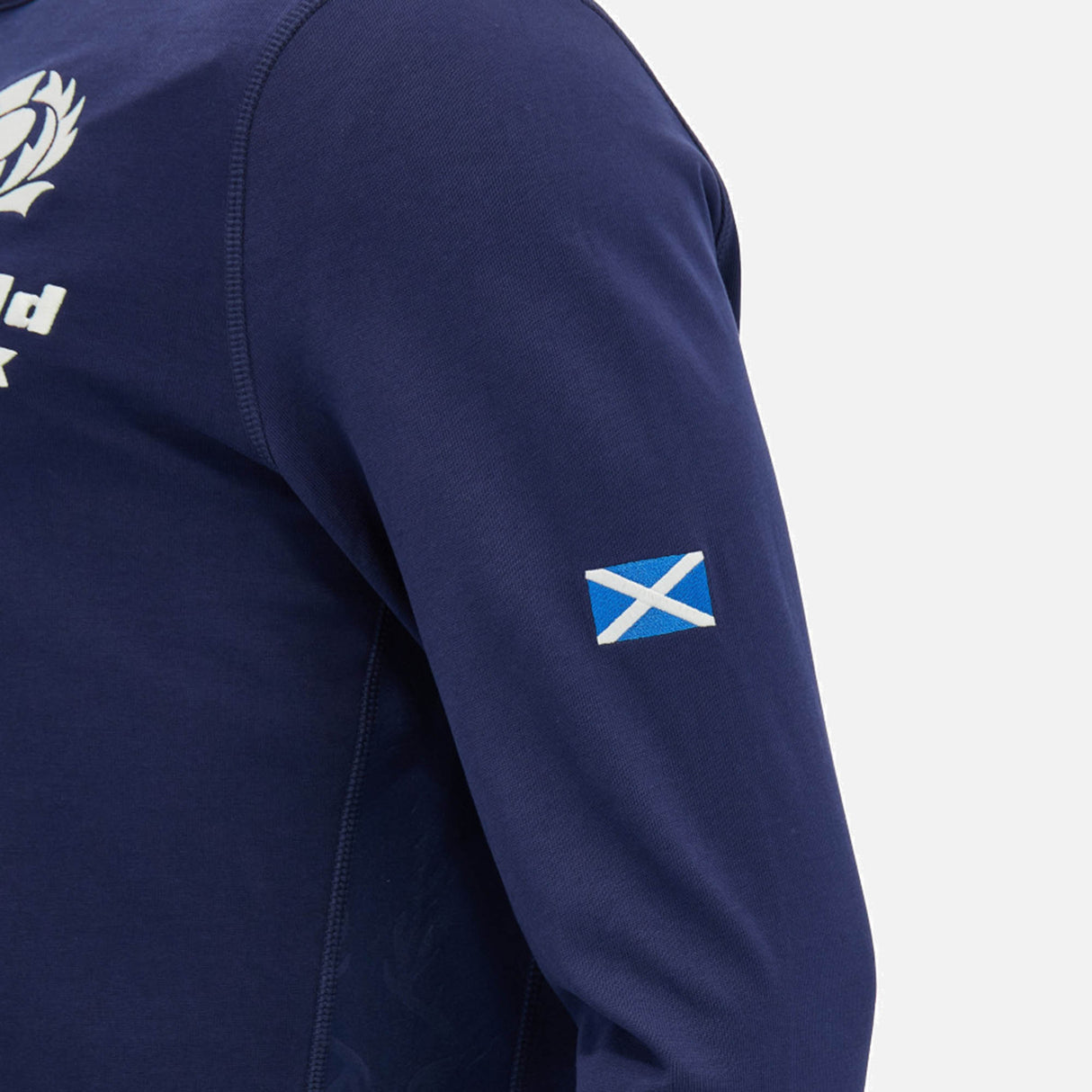 A person wearing the Scotland SRU 26/27 Cotton Replica Long Sleeve Home Jersey by Macron, featuring a small Scottish flag patch on the upper arm.