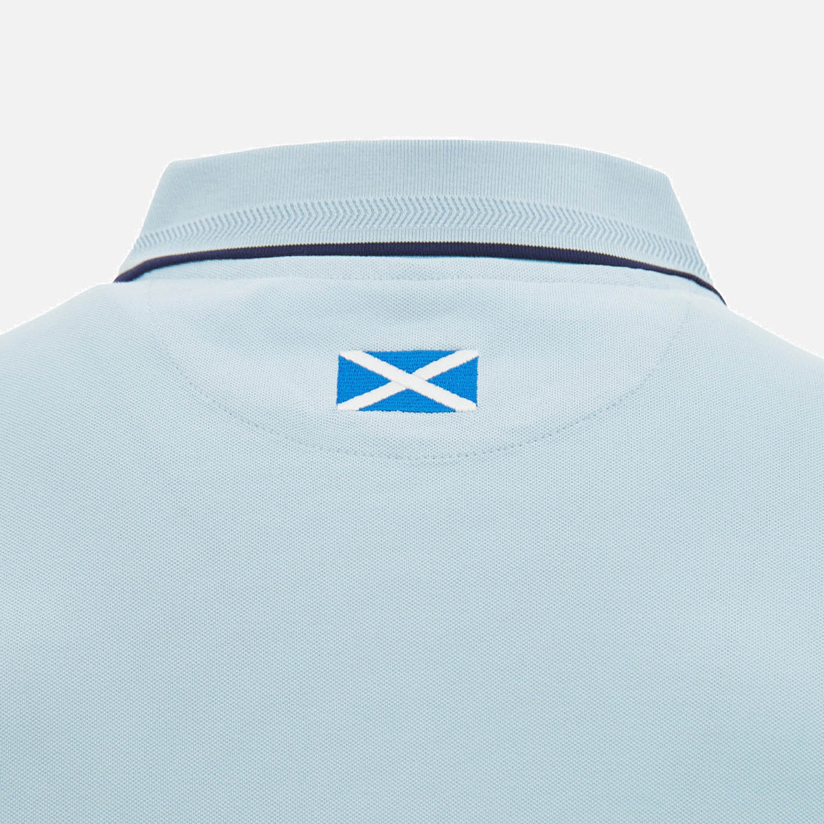 Close-up of the back collar of the Scotland SRU 26/27 Travel Polo by Macron in light blue, featuring a small Scotland flag patch below the collar.