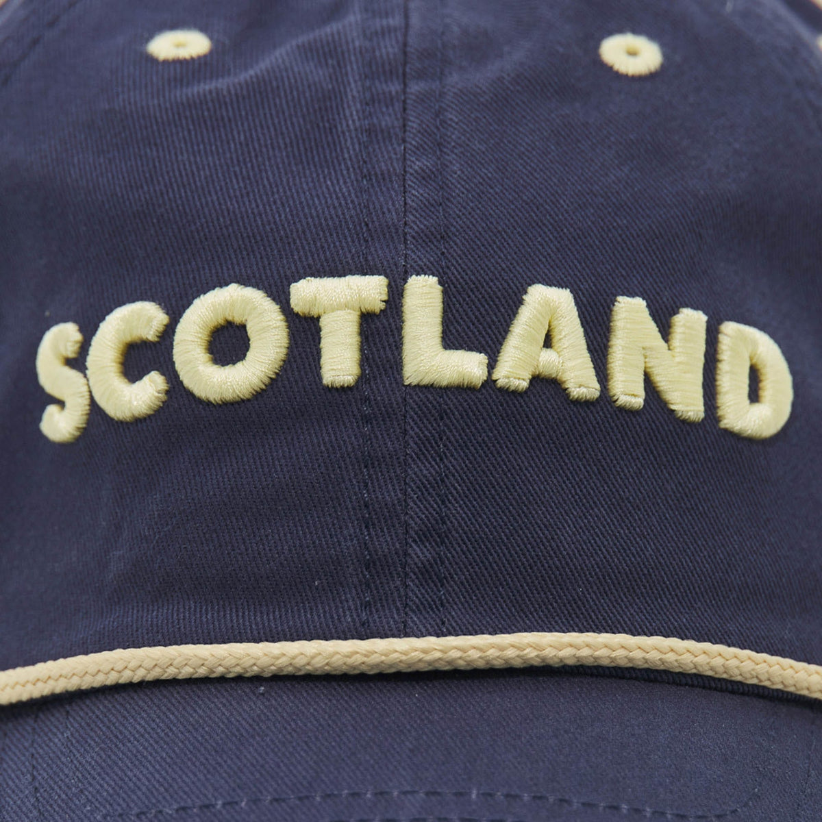 Show your support with the Scotland SRU 26/27 Dad Cap by Macron. Featuring "SCOTLAND" embroidered in bold yellow letters on the front above a striking yellow trim, this official navy blue cap blends stylish design with team spirit—an ideal accessory for any Scotland Rugby fan.
