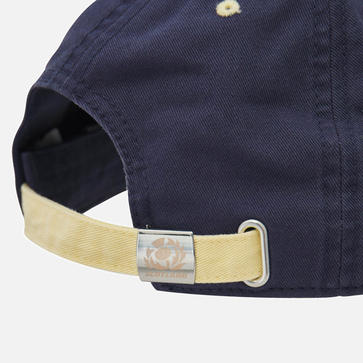 Close-up of the back of the Scotland SRU 26/27 Dad Cap by Macron, an official Scotland Rugby cap for the 26/27 season. It features a light tan adjustable strap and a metal clasp embossed with a thistle logo and the word "Scotland.