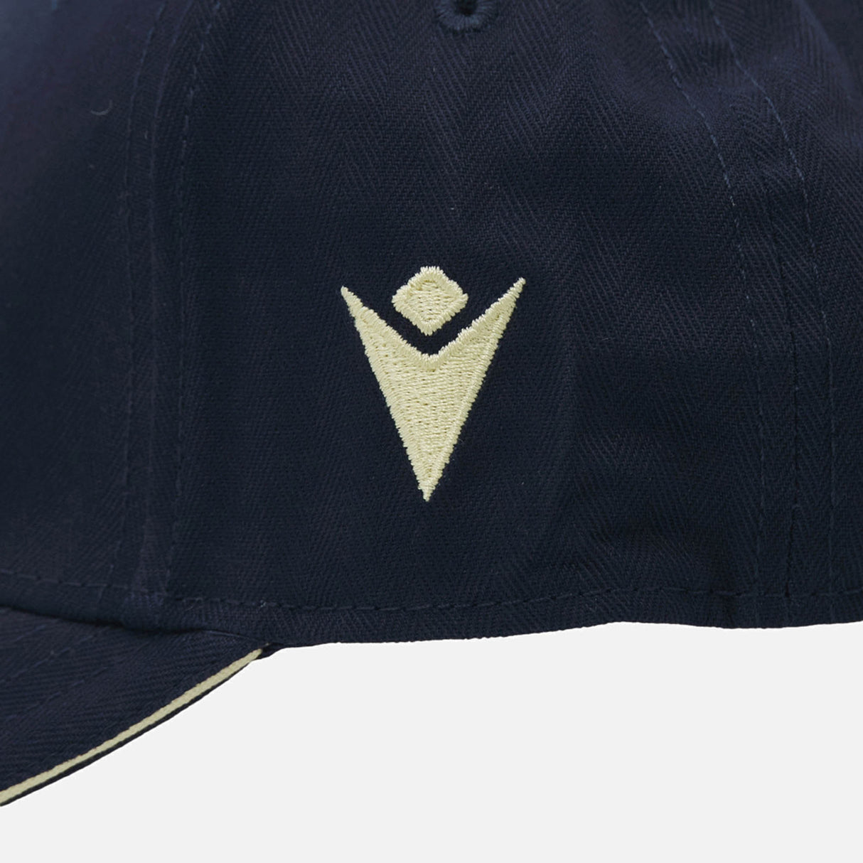 Close-up of the Scotland SRU 26/27 Thistle Baseball Cap by Macron in navy blue, featuring a cream-colored, embroidered geometric thistle logo on the front panel.