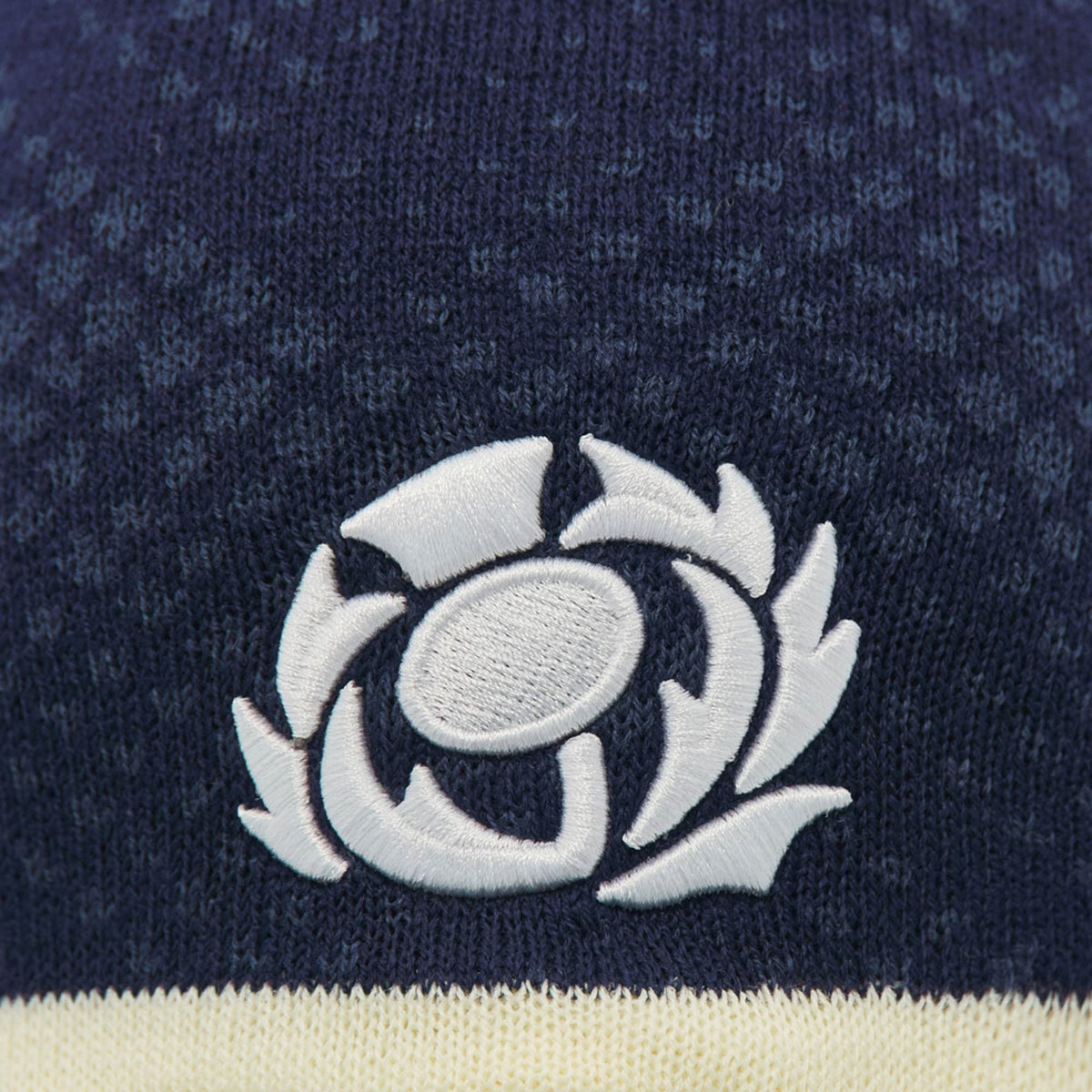 Close-up of the Scotland SRU 26/27 Knit Beanie by Macron in navy blue, featuring the white Scottish Rugby Union logo embroidered on the fabric, highlighting the quality craftsmanship of this Macron beanie.