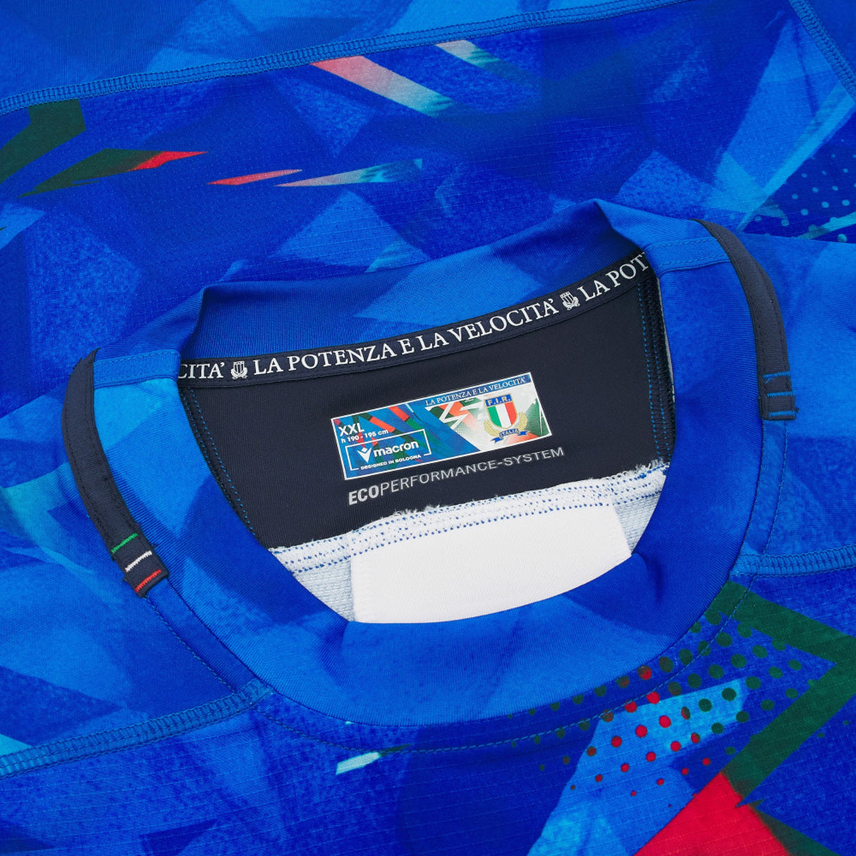 Close-up of the Italy 26/27 Home Authentic Jersey by Macron in blue, highlighting the collar with a visible Macron label, size details, and the phrase “LA POTENZA E LA VELOCITÀ” printed inside the neckline for an authentic touch.