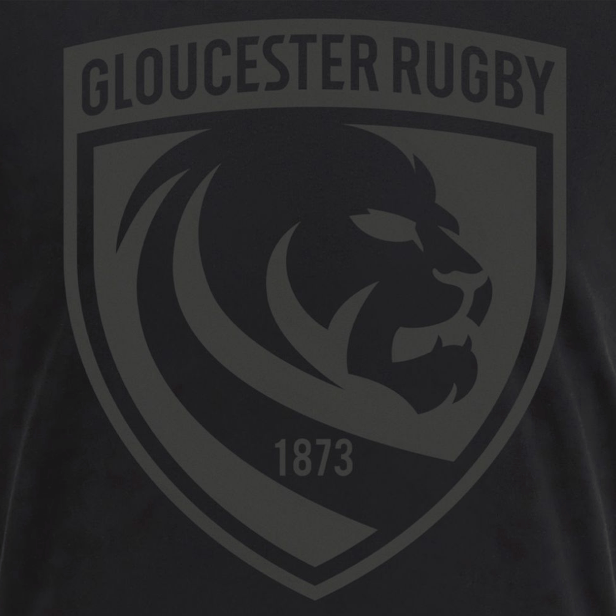 Show your support with the Gloucester 25/26 Cotton Travel T-Shirt by Macron, featuring a black and gray shield logo with a lion's head, "GLOUCESTER RUGBY" at the top, and "1873" at the bottom—perfect for your collection.