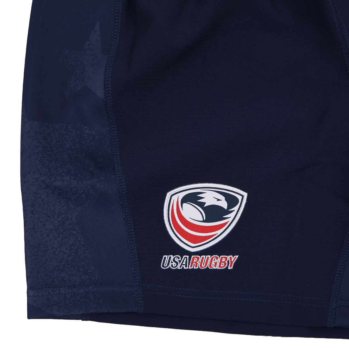 Close-up of USA Rugby 24/25 Home Shorts by Macron in navy blue, featuring moisture-wicking fabric and the USA Rugby eagle logo with "USA Rugby" text on the lower left side.