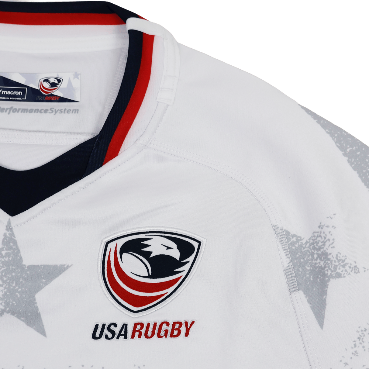 The Women's USA Rugby 24/25 Away Body Fit Jersey by Macron features the USA Rugby eagle logo, "USA RUGBY" text, a red and black collar, and gray star shoulder details—ideal for fans or players supporting USA Rugby.