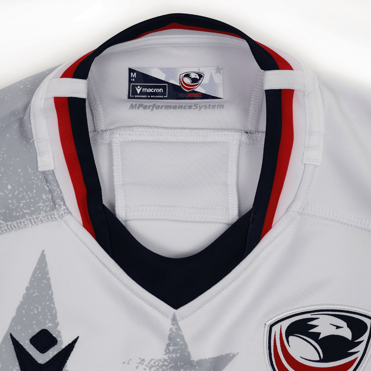 Close-up of the collar and upper chest on the Women's USA Rugby 24/25 Away Bodyfit Shirt by Macron, featuring red and black accents, an eagle logo on the shoulder, and a size M label.