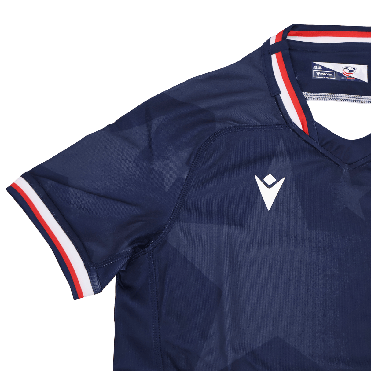 The Youth USA Rugby 24/25 Home Jersey by Macron features a navy blue design with a subtle star pattern, white Macron logo, and red, white, and blue trim—perfect for young fans of the USA Rugby style.