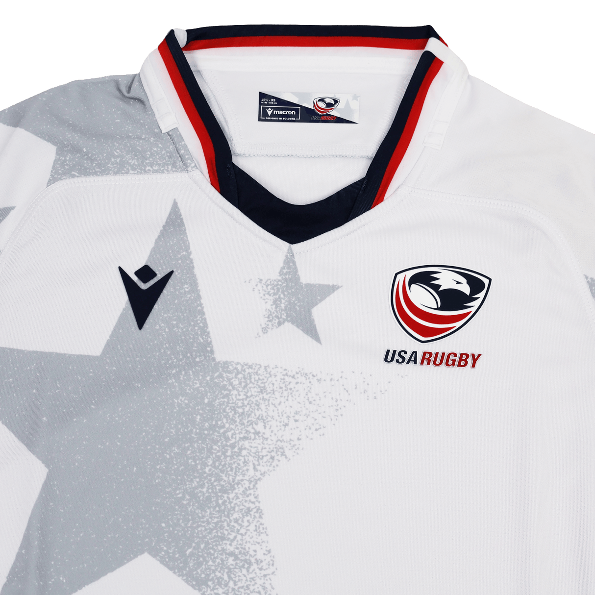 The Youth USA Rugby 24/25 Away Jersey by Macron features a white base with a bold gray star pattern, USA Rugby and Macron logos on the chest, and red, white, and blue collar trim.