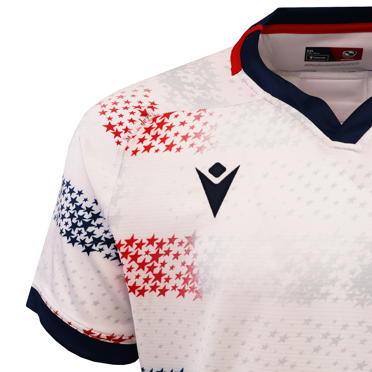 A close-up of the USA Rugby 25/26 Home Body Fit Match Jersey by Macron, featuring a white design with red and blue star patterns, a navy collar, and a black chest logo.