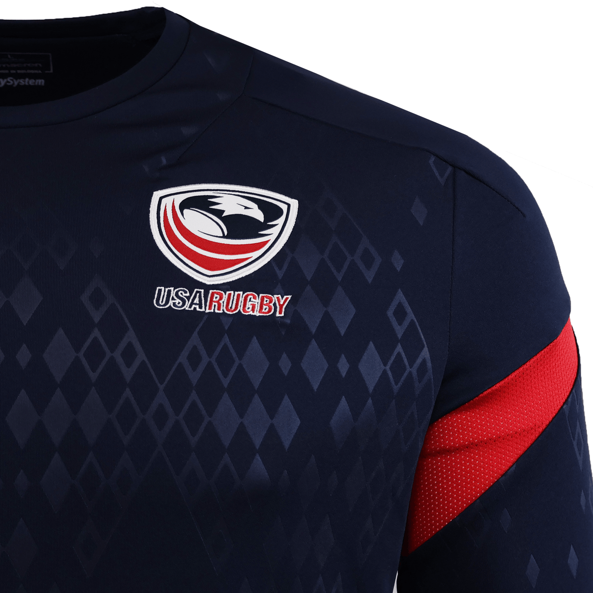 Close-up of the USA Rugby 25/26 LS Training Poly Shirt by Macron, in navy blue with red sleeve accents and a white, red, and blue eagle logo. This polyester shirt delivers comfort and durability for dedicated fans.