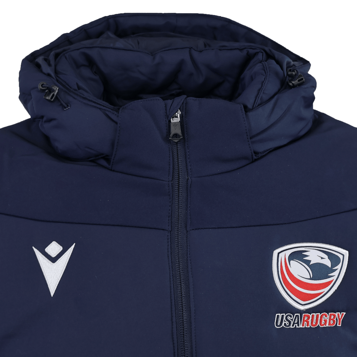 The USA Rugby 25/26 Padded Jacket by Macron is a navy blue jacket with a front zipper, featuring the USA Rugby logo on the right chest and a white Macron logo on the left chest.