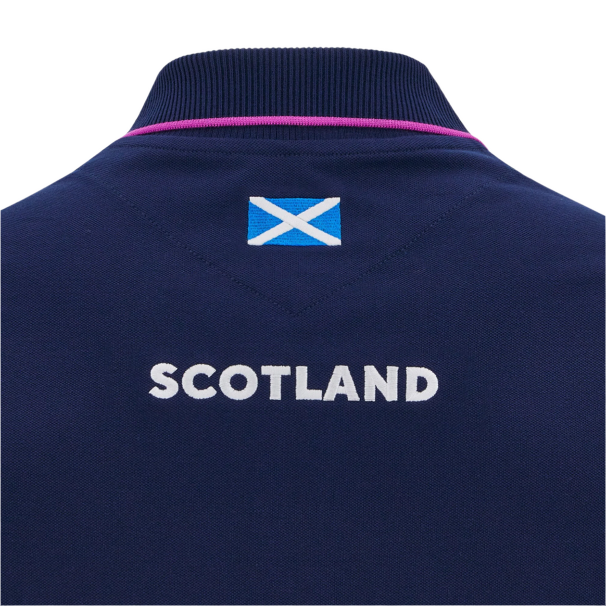 The Macron Scotland 25/26 Player Travel Cotton Polo is navy blue with "SCOTLAND" and a small Scottish flag printed on the upper back below the collar.