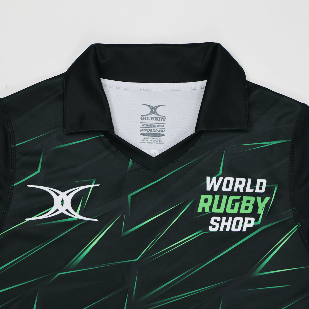 The Gilbert Sublimated Pro Collared Jersey - Womens by Teamatical is a black rugby jersey with green and white diagonal lines, featuring the Gilbert logo on the left chest and “WORLD RUGBY SHOP” on the right.