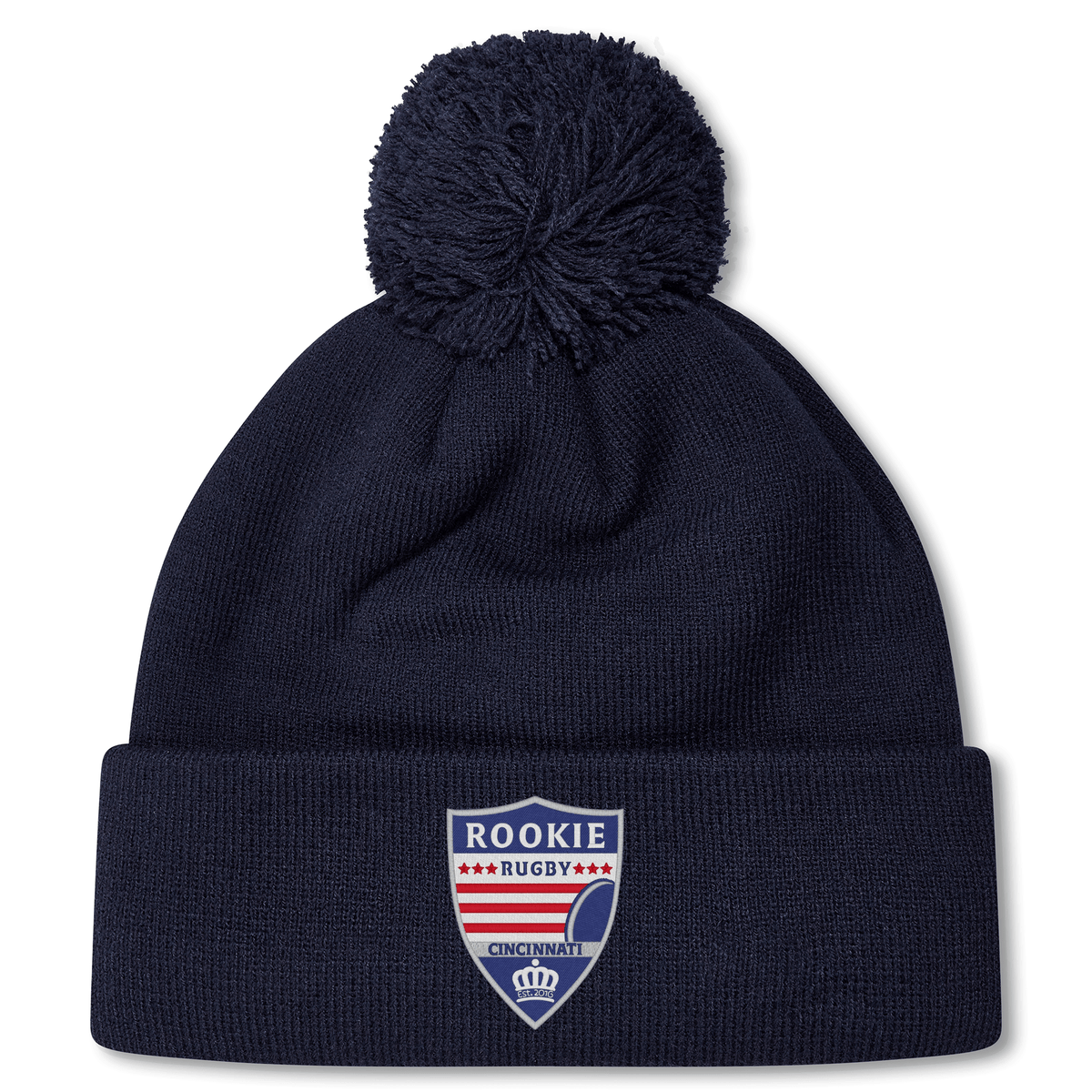 A navy blue beanie with a pom-pom on top, featuring a "Rookie Rugby Cincinnati" logo on the front. This Cincinnati Rookie Rugby Pom Pom Beanie by Canterbury is fleece-lined for extra warmth and comfort.