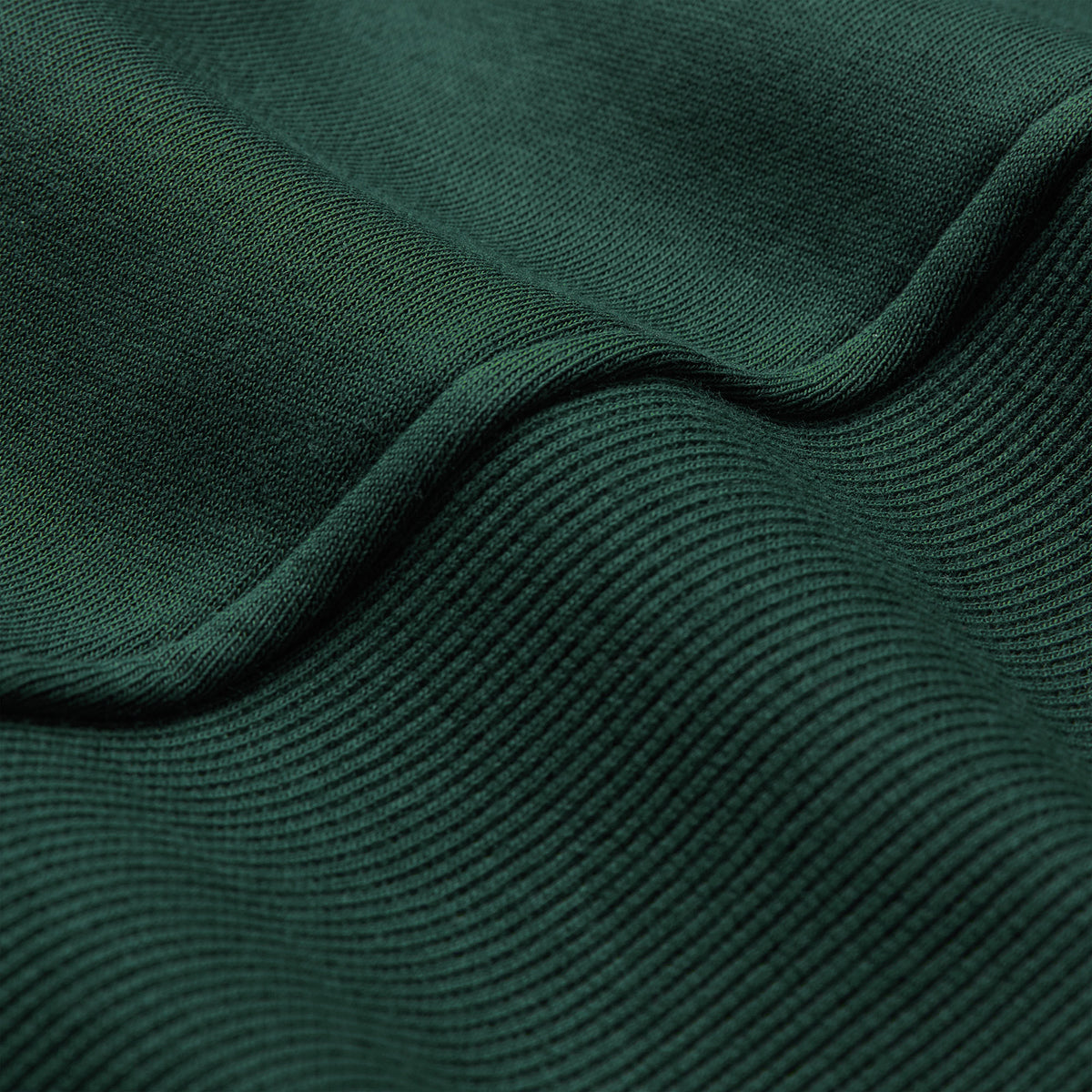 Close-up of dark green ribbed fabric from the Ireland 26 Leisure Hoodie by Canterbury, highlighting its texture and gentle folds.