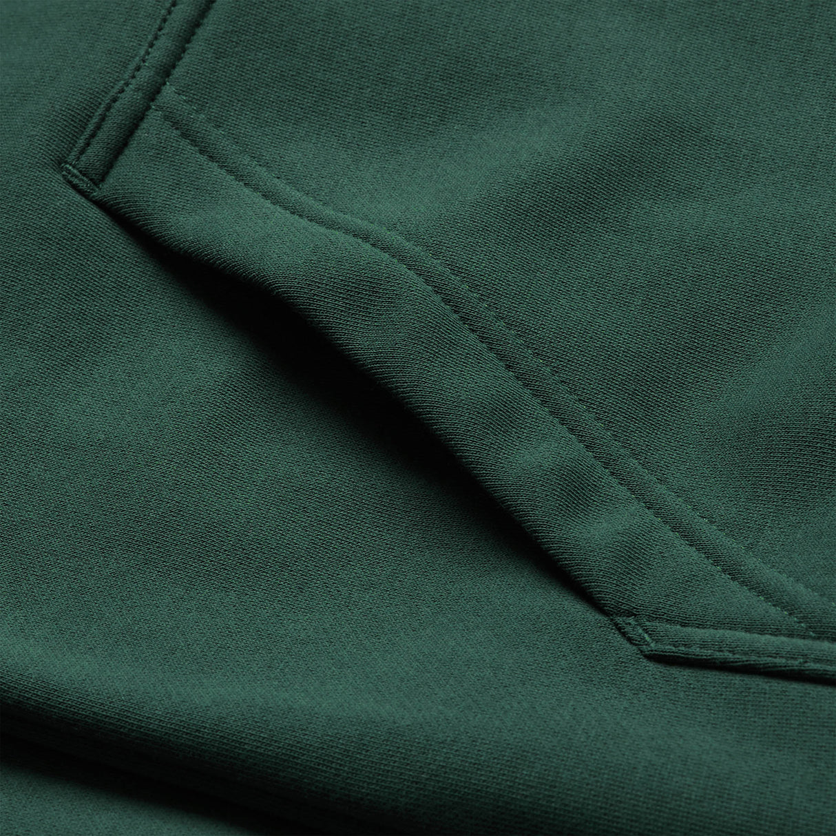 A close-up of the Ireland 26 Leisure Hoodie by Canterbury in forest green, showcasing the pocket’s textured fabric and double-stitched seams—a testament to Canterbury’s renowned quality craftsmanship.