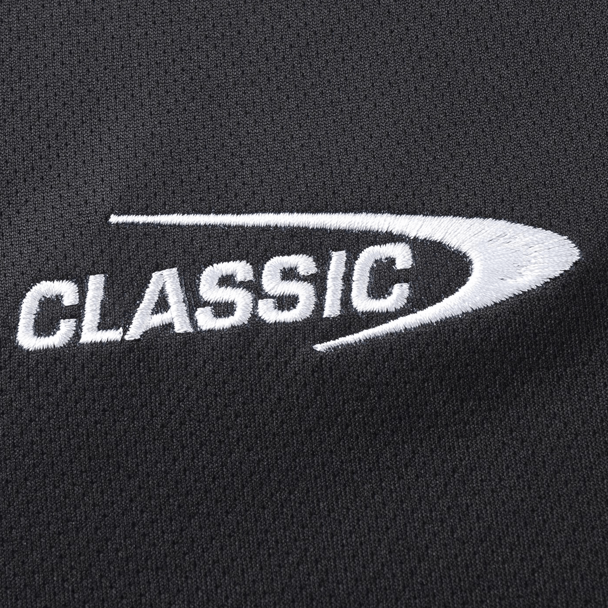 Close-up of white "CLASSIC" embroidery with a curved line on black, moisture-wicking fabric, evocative of the Crusaders Super Rugby Team Polo 25/26 by Classic Sportswear.
