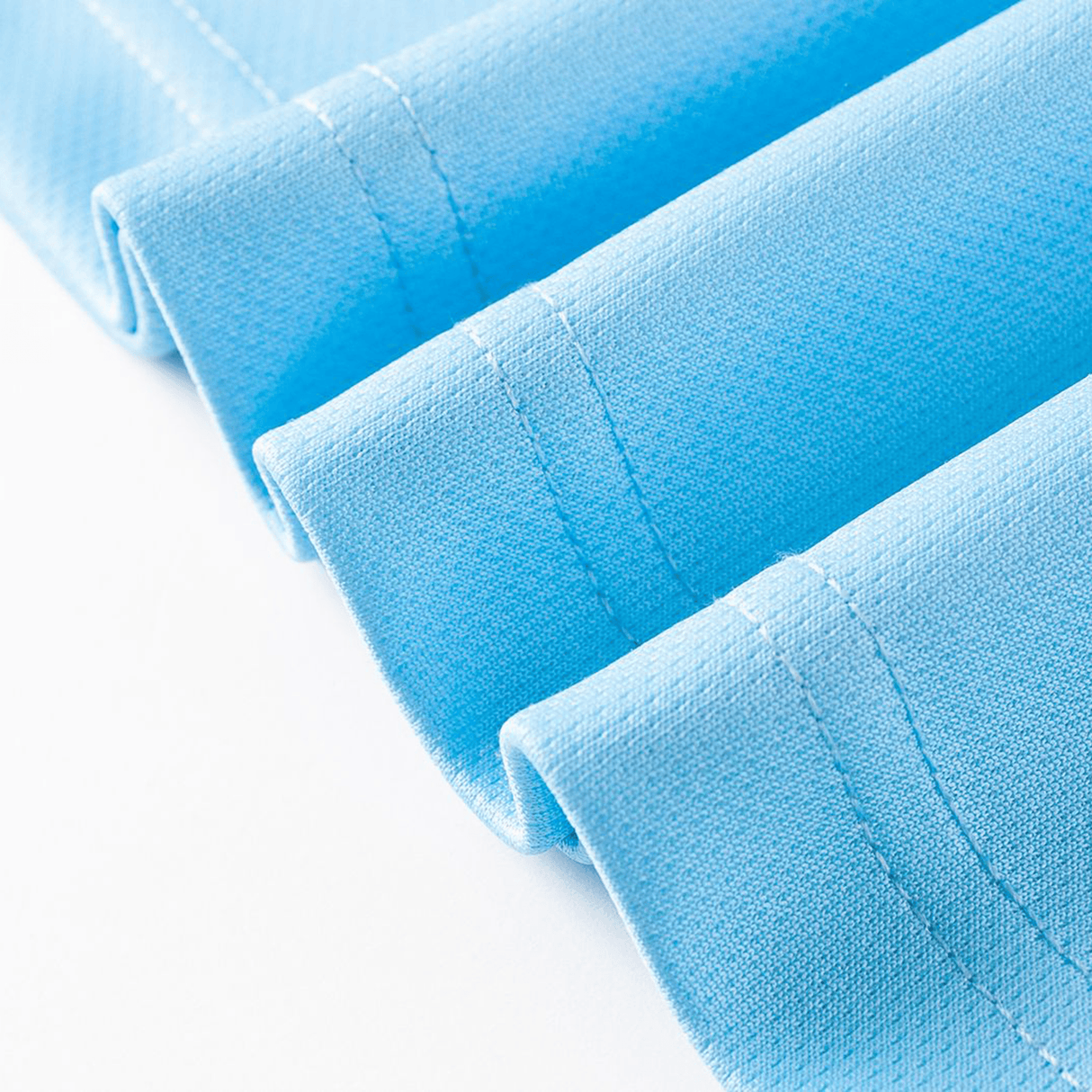 Close-up of neatly folded light blue fabric, resembling the Sharks NRL 26/27 Replica Home Jersey by Classic Sportswear, featuring visible stitching and textured surface on a white background.