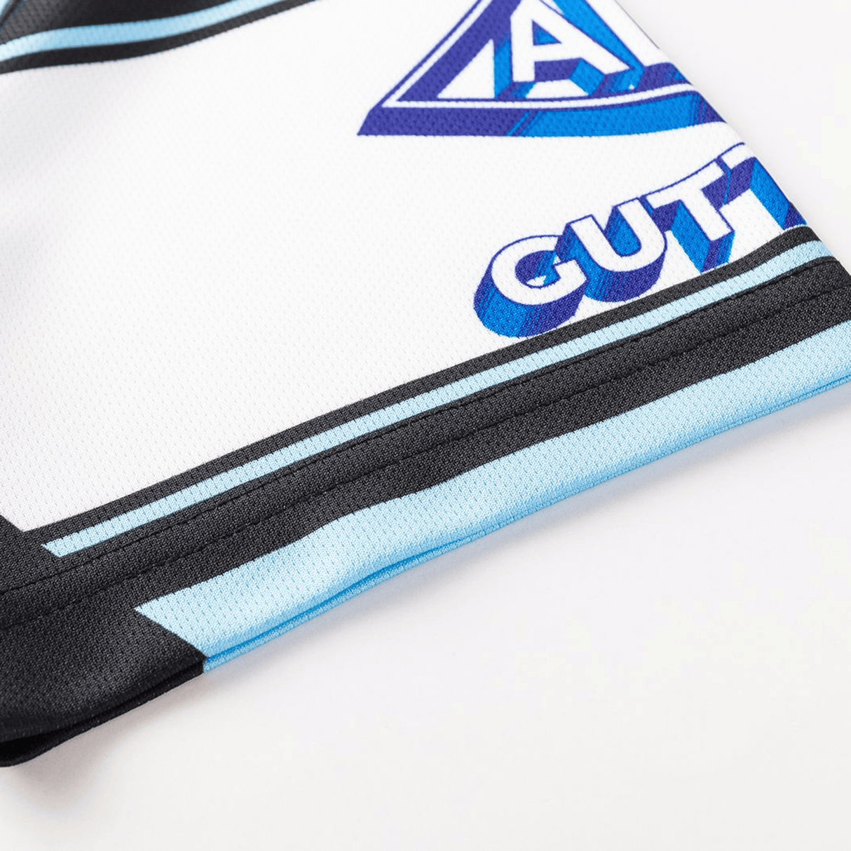 Close-up of the Sharks NRL 26/27 Replica Home Jersey by Classic Sportswear, showing a geometric blue-purple logo, "GUTT" text, and black and blue accents on crisp white fabric.
