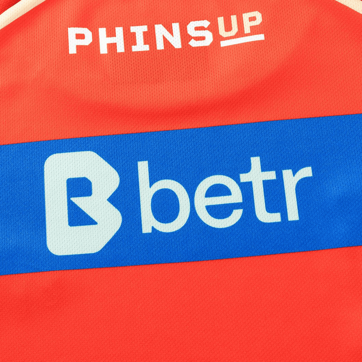 Close-up of the Dolphins NRL 26/27 Replica Home Jersey by Classic Sportswear—authentic red design with "PHINS UP" at the top and a blue stripe featuring the "betr" logo.