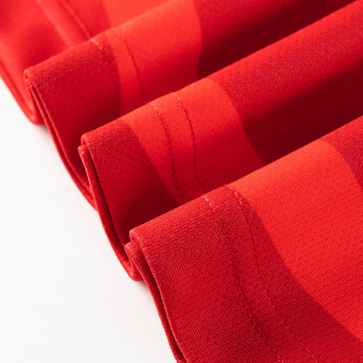 Close-up of folded red fabric with visible stitching and a subtle wavy pattern, reflecting the craftsmanship of the Dolphins NRL 26/27 Replica Home Jersey by Classic Sportswear.