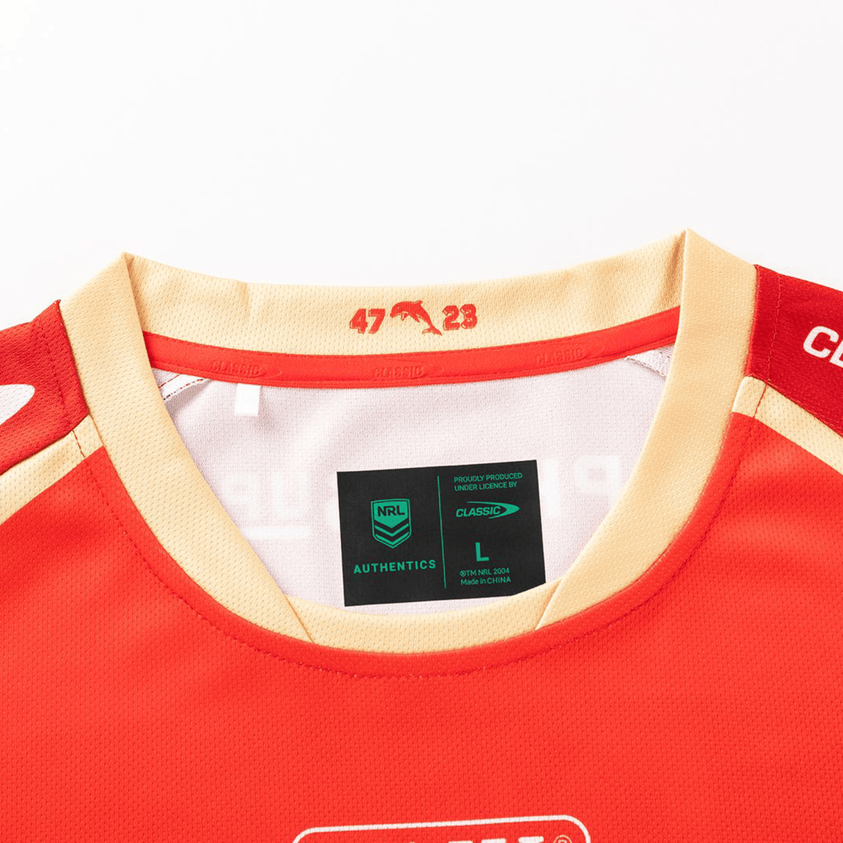 A close-up of the collar and shoulder of the Dolphins NRL 26/27 Replica Home Jersey by Classic Sportswear, showing size and authenticity labels, with "47" and "23" printed inside the collar.