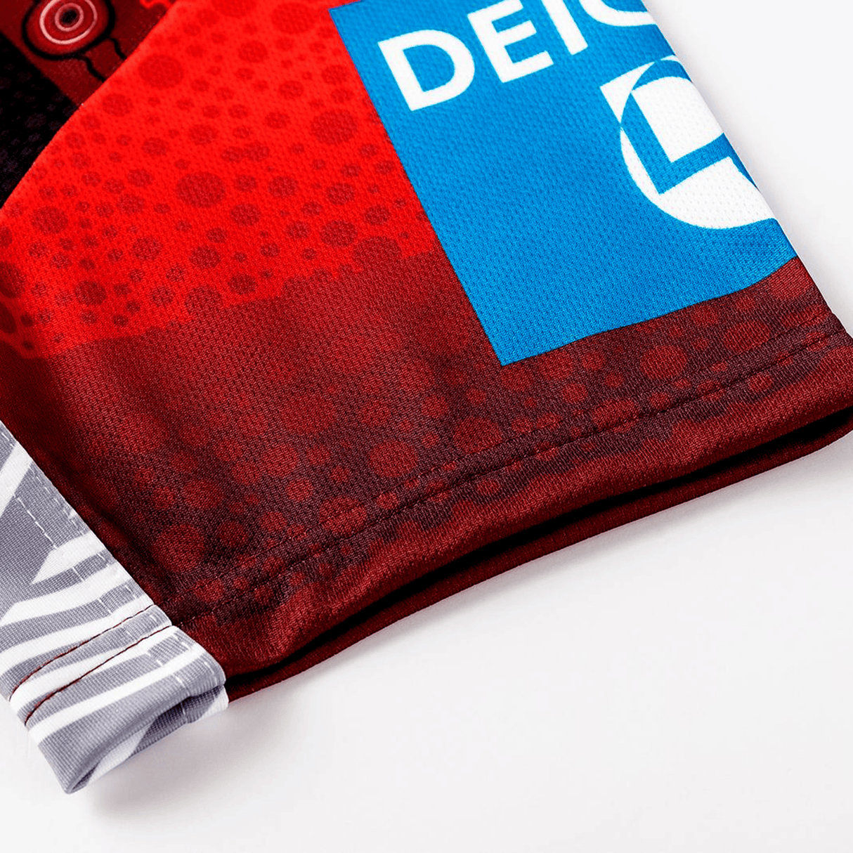 Close-up of the Dragons Indigenous NRL 25/26 Replica Jersey by Classic Sportswear, showing red and black geometric patterns and a blue rectangular "DEICH" logo.