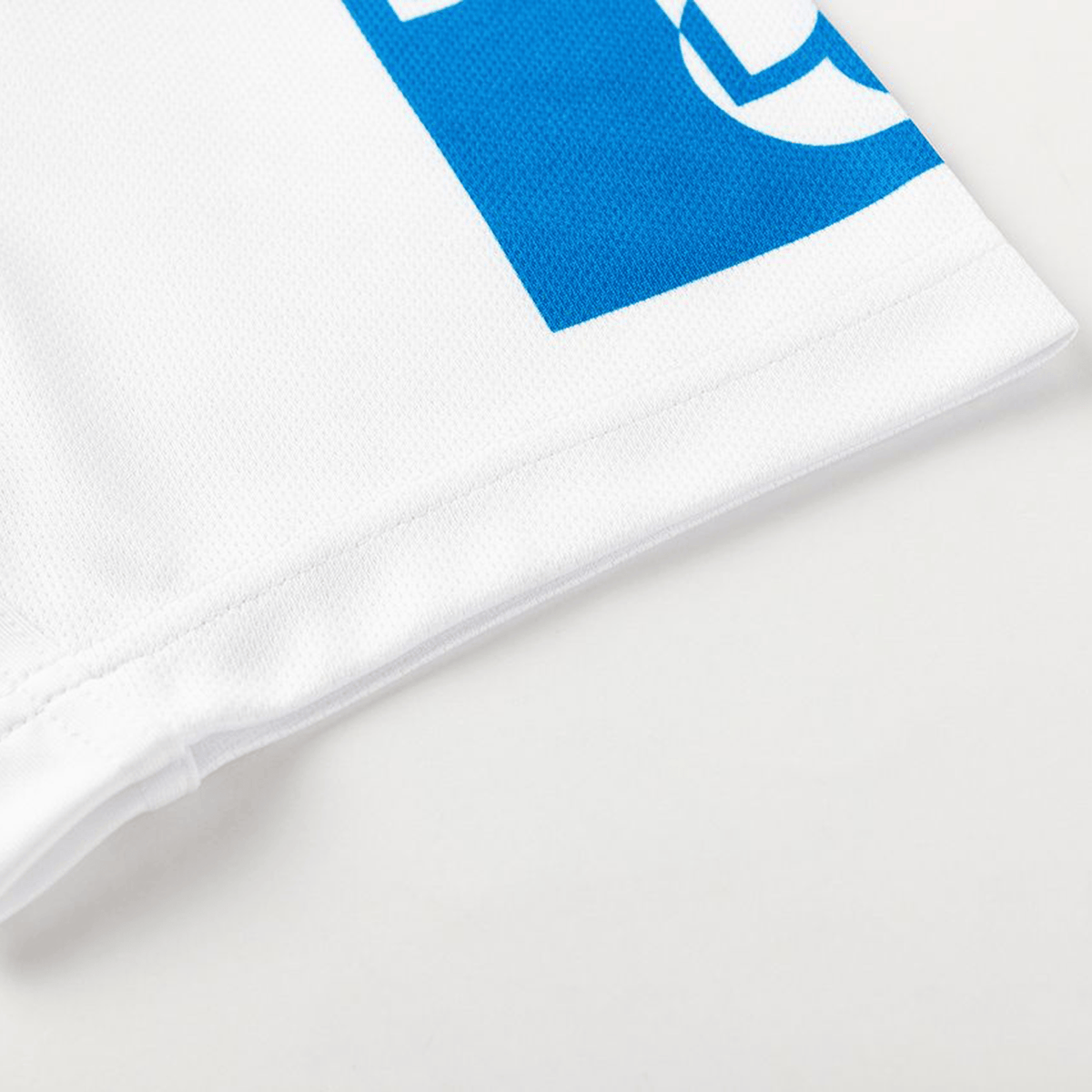 Close-up of the lower edge of the Dragons NRL 26/27 Replica Home Jersey by Classic Sportswear, featuring a partial blue graphic design on a plain background.
