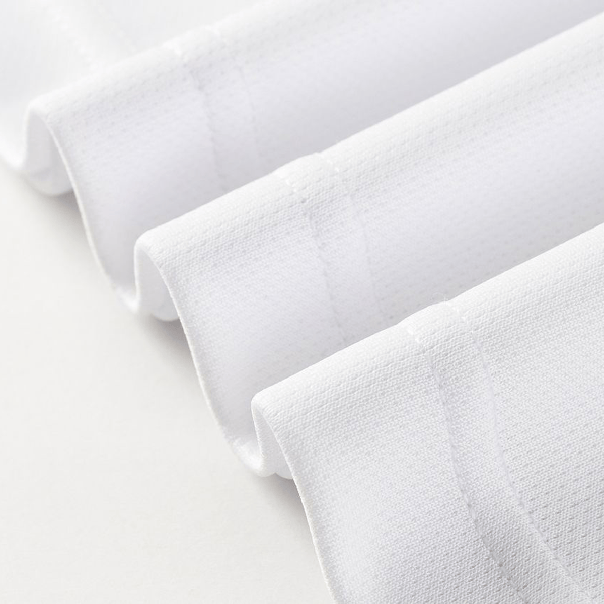 Close-up of four neatly folded edges of white textured fabric, echoing the craftsmanship found in the Dragons NRL 26/27 Replica Home Jersey by Classic Sportswear, arranged in parallel lines on a light surface.