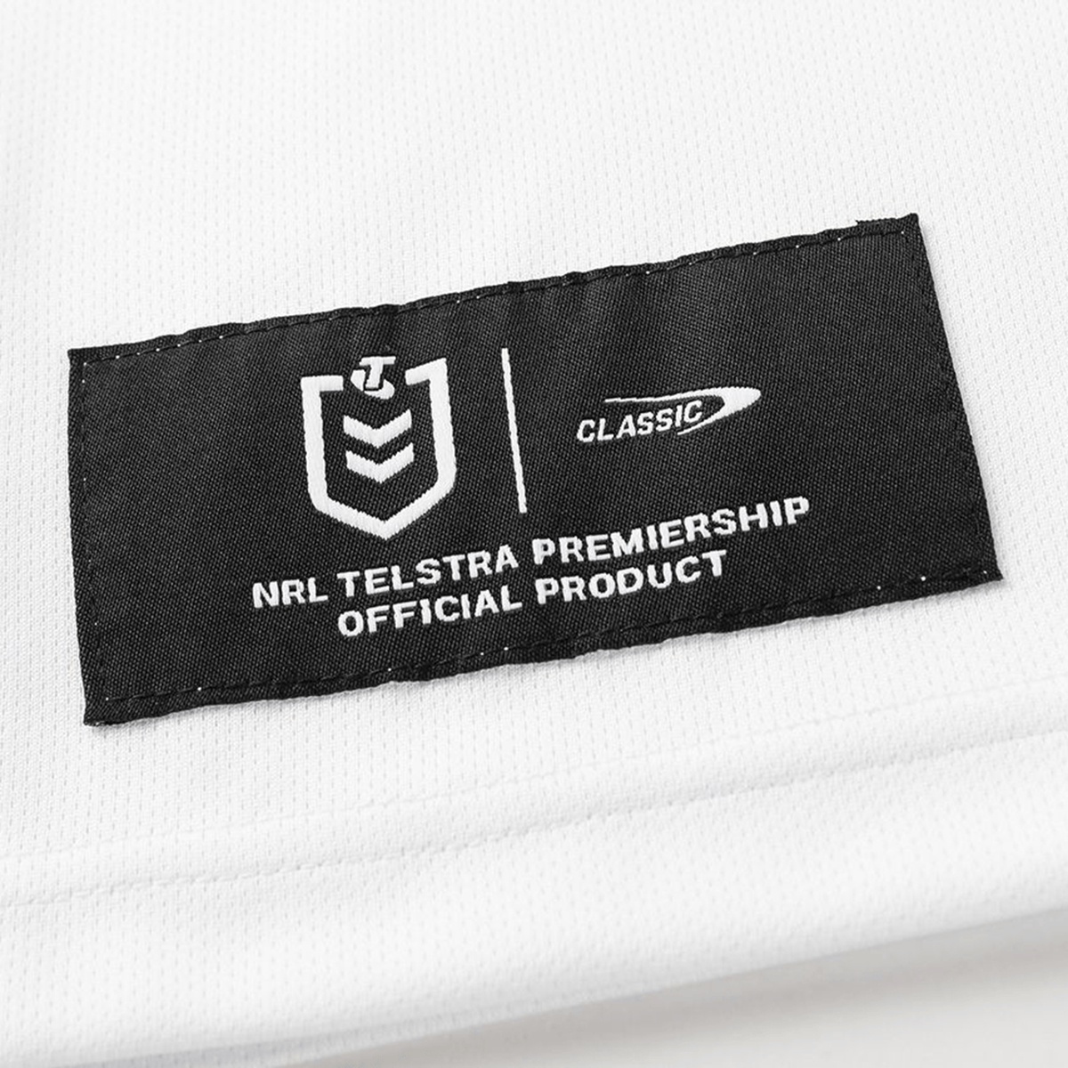 A black label on white fabric reads "NRL Telstra Premiership Official Product" with NRL and Classic Sportswear logos, featured on the Dragons NRL 26/27 Replica Home Jersey by Classic Sportswear.