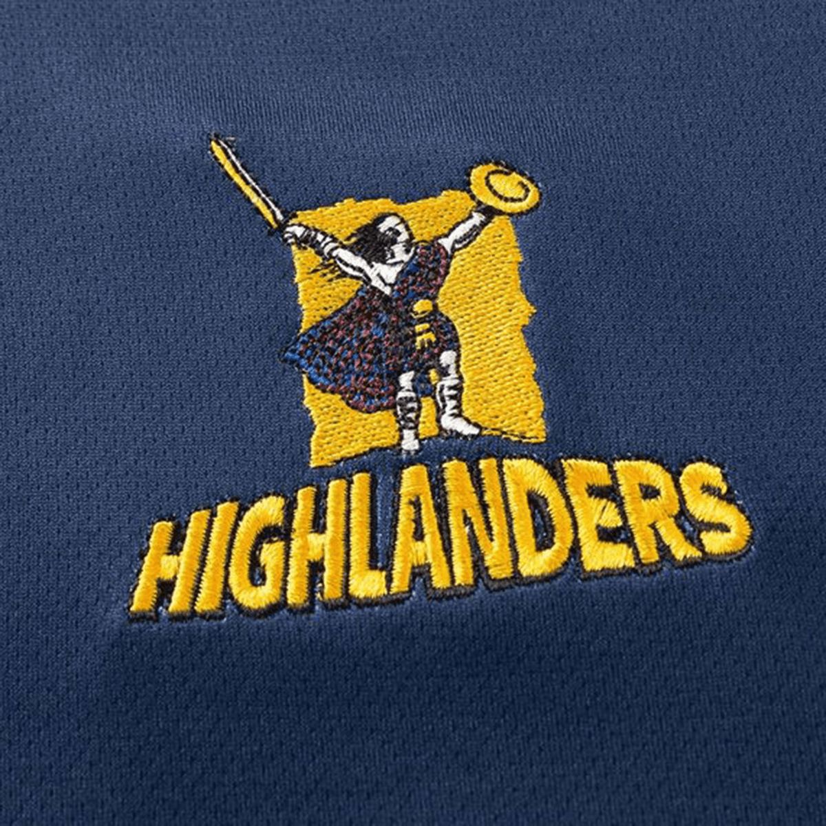 Moisture-wicking dark blue rugby polo by Classic Sportswear features an embroidered logo of a warrior with sword and shield above "Highlanders," celebrating the spirit of Highlanders Super Rugby. Name: Highlanders Super Rugby Team Polo 25/26.