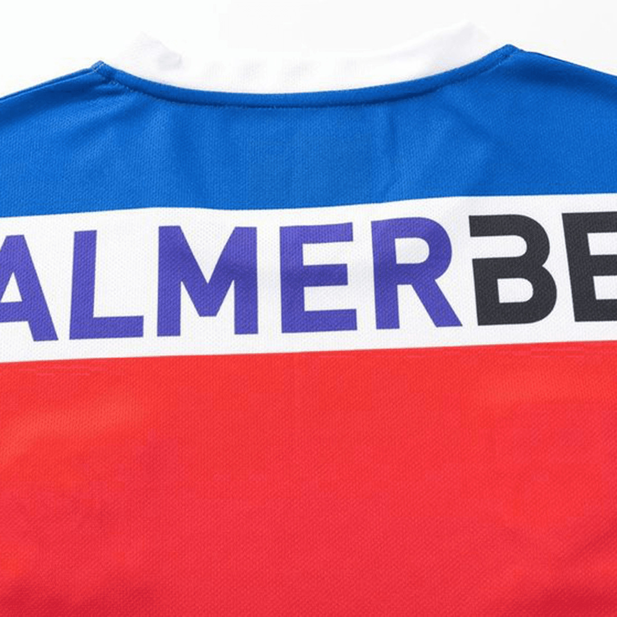The Knights NRL 25/26 Replica Home Jersey by Classic Sportswear boasts an athletic fit, accented with vibrant blue, white, and red sections. The dynamic design is enhanced by sublimated graphics featuring the partial text "ALMER BE.