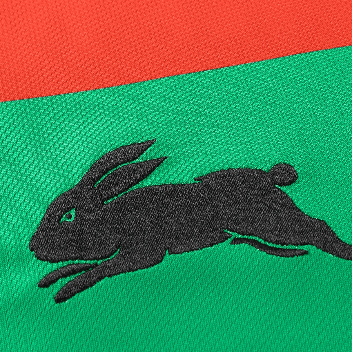 Classic Sportswear's Rabbitohs NRL 25/26 Replica Home Jersey showcases a sleek black rabbit logo on a vibrant green and red background.