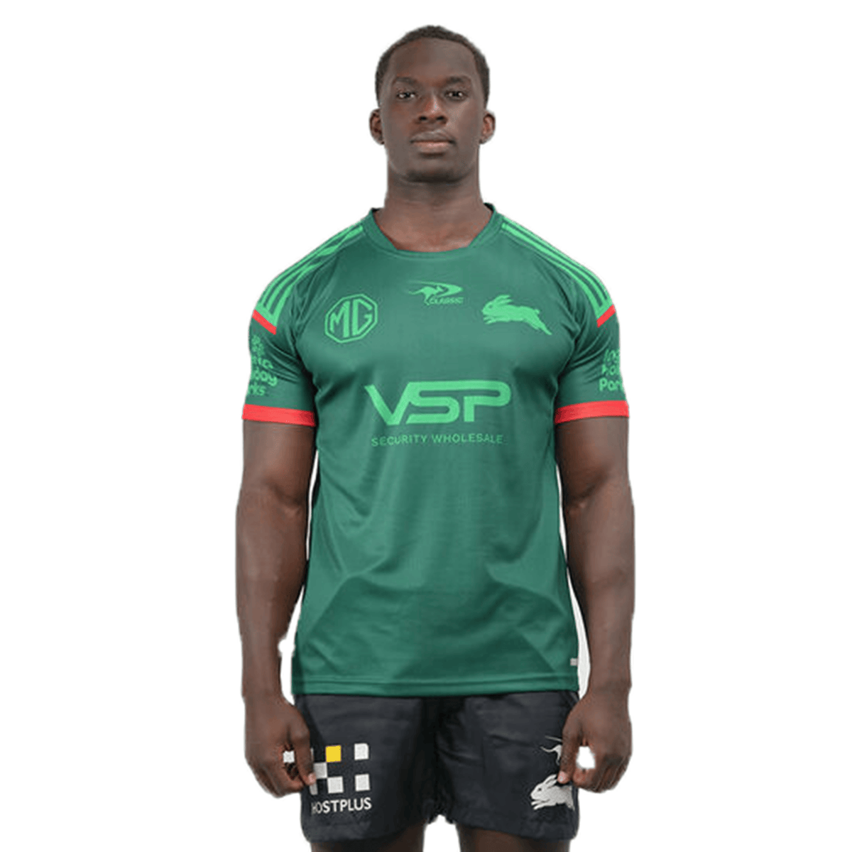 The person is wearing the Rabbitohs NRL 25/26 Special Edition Captains Run Jersey by Classic Sportswear, matched with black shorts, against a pristine white backdrop.