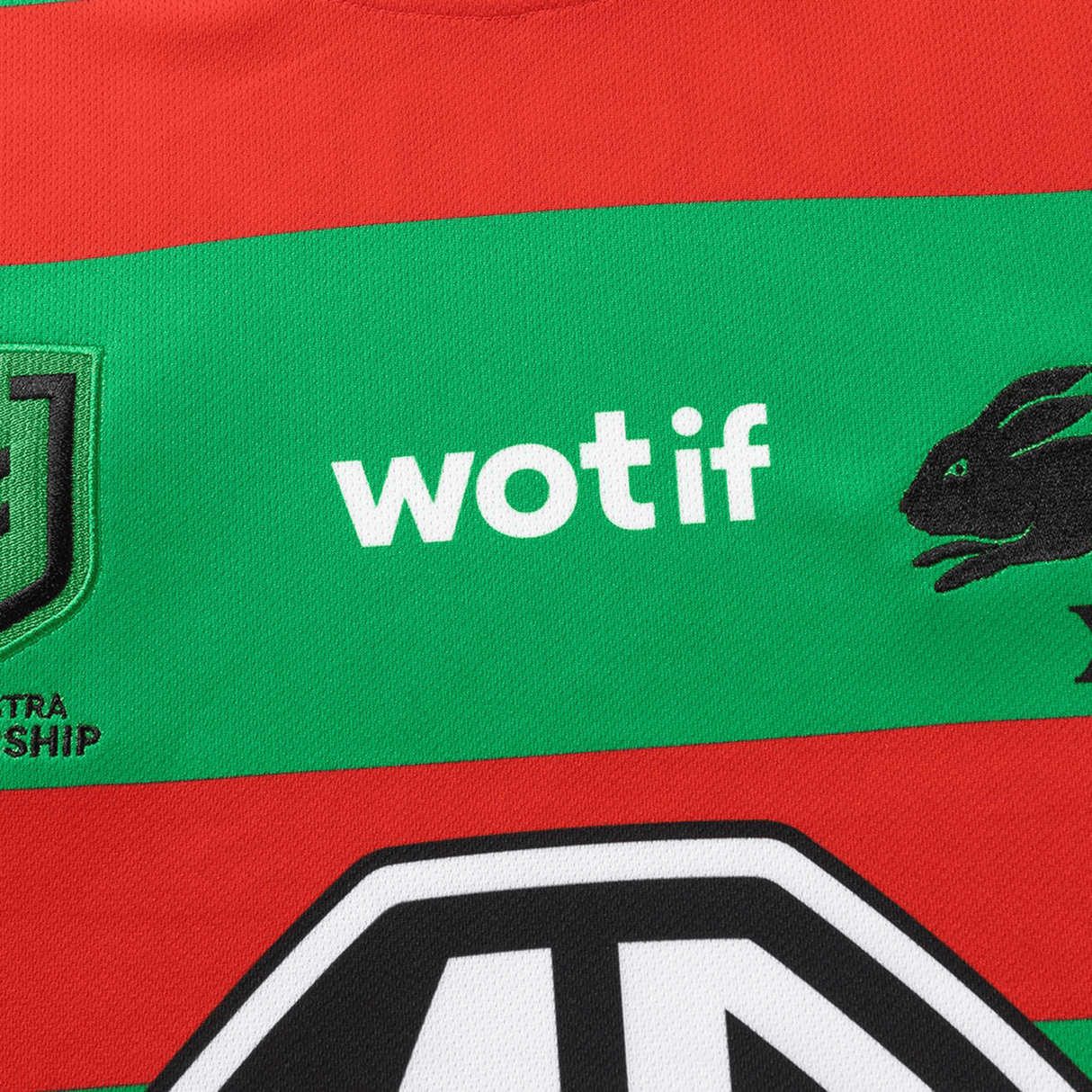 Close-up of the Rabbitohs NRL 26/27 Replica Home Jersey by Classic Sportswear, featuring red and green stripes, "wotif," rabbit logo, shield emblem, and partial "TRO SHIP" text—ideal rugby performance apparel.