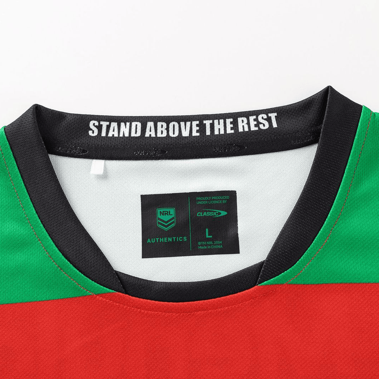 Close-up of the Rabbitohs NRL 26/27 Replica Home Jersey by Classic Sportswear shows the collar with "STAND ABOVE THE REST" inside, plus "NRL AUTHENTICS" and size "L" label details.