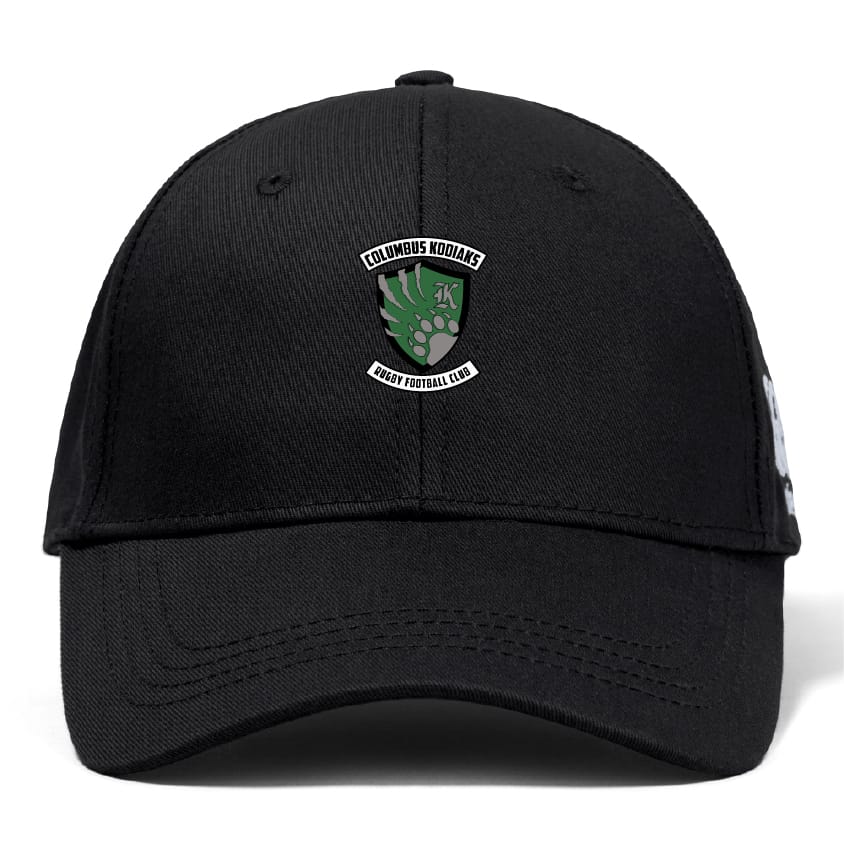 The Columbus Kodiaks Full Color Logo Flexfit Drill Cap by EMB Canterbury is a black cap with a curved brim, featuring an embroidered green bear paw and shield logo on the front.